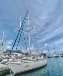 Spacious saloon with cushioned seating, wood panels and bookshelves on Amel Maramu sailboat in Panama