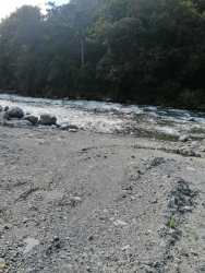 Open grassy land bordered by flowering shrubs and mountain landscape in Volcán Bambito Panama