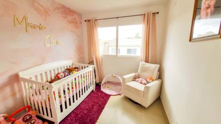 Cozy nursery with crib, armchair and large window in Costa Verde family home