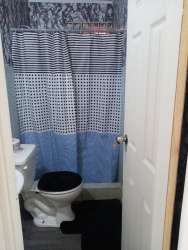 Small bathroom with striped curtain, toilet and sink Villa Nazareth Puerto Caimito