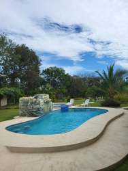 Outdoor swimming pool with waterfall, garden landscaping and greenery in Penonomé countryside house