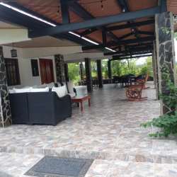 Covered patio with sofa, dining table, stone pillars, rustic decor in Penonomé rental house