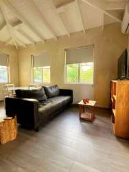Bright living room with black sofa, wood flooring, vaulted ceiling El Ciruelo Residences Playa Venao Panama