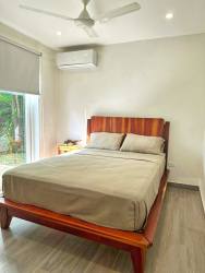 Bright bedroom with large windows, ceiling fan, wood flooring at El Ciruelo Residences Playa Venao Panama