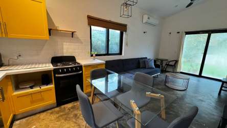 Modern minimalist bedroom with large windows, ceiling fan and AC overlooking garden in Playa Venao Panama