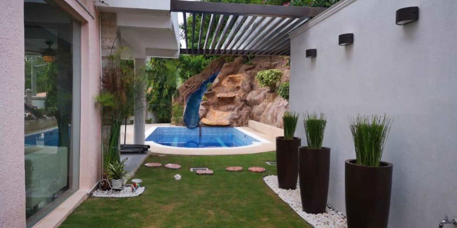 Outdoor kitchen with tiled bar, grill, wood accent wall, and plants Colonia Fuente del Fresno