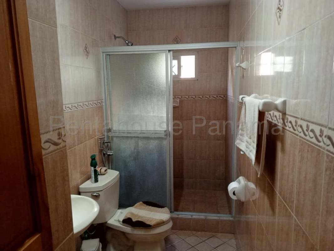 Bedroom with tiled floor, wooden closet and window lighting in Camino Real Betania house