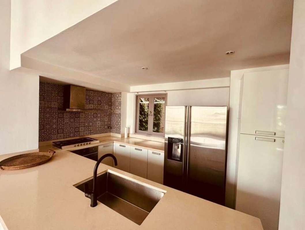 Modern kitchen with beige counters, blue tile backsplash, stainless steel fridge Casco Viejo Panama