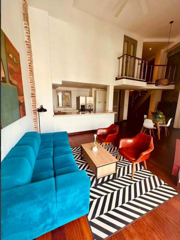 Rustic contemporary loft in Casco Viejo with stone walls, wood stairs, dining space