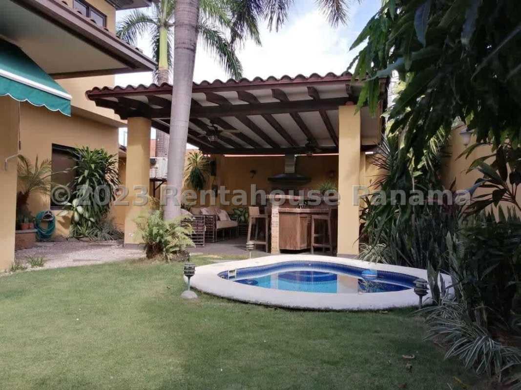 Tropical backyard with small circular pool, grass, covered patio Costa del Este luxury house Panama