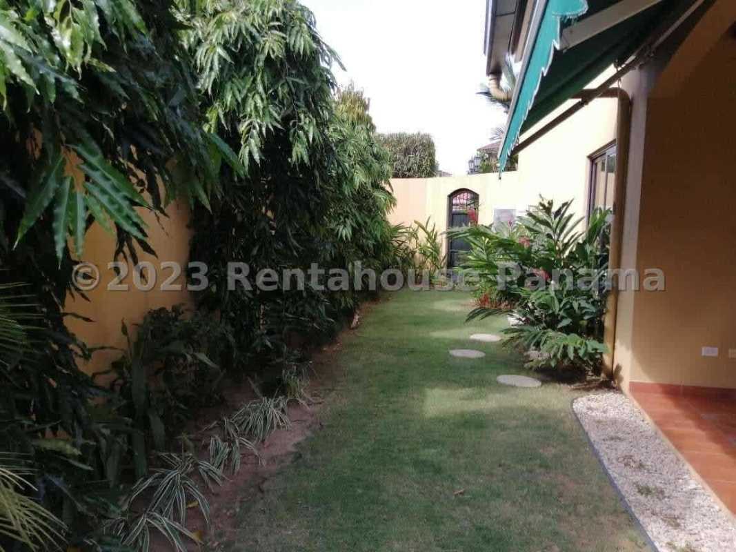 Side yard with lush landscaping, green lawn, shaded patio space Costa del Este luxury house