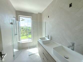 Luxury bathroom with dual vessel sinks, glass shower and large window overlooking greenery