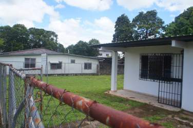 Large fenced lot with grassy lawn and trees in commercial area David