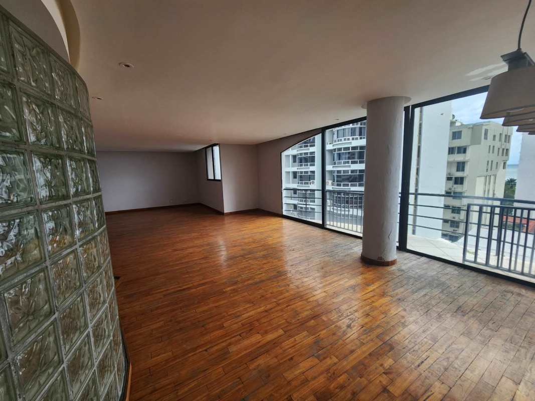 Modern living room with wood floors, large windows, balcony, curved glass block wall in PH La Caleta Penthouse Panama