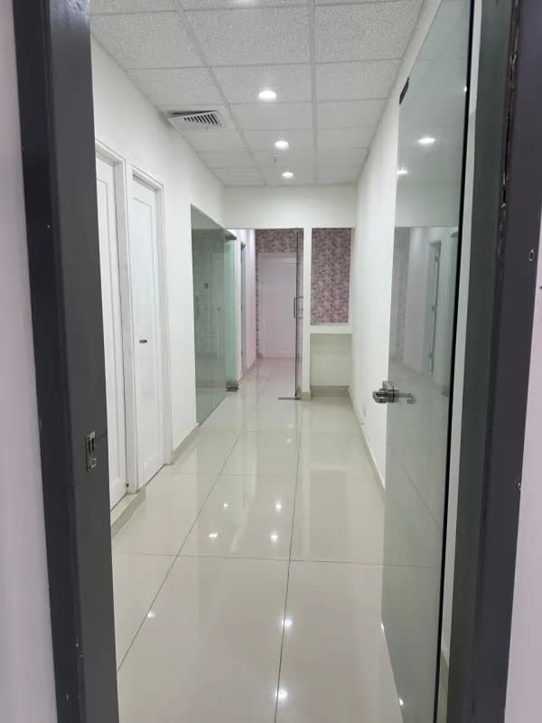 Clean hallway with tiled floor and glass doors inside Panama Design Center office space