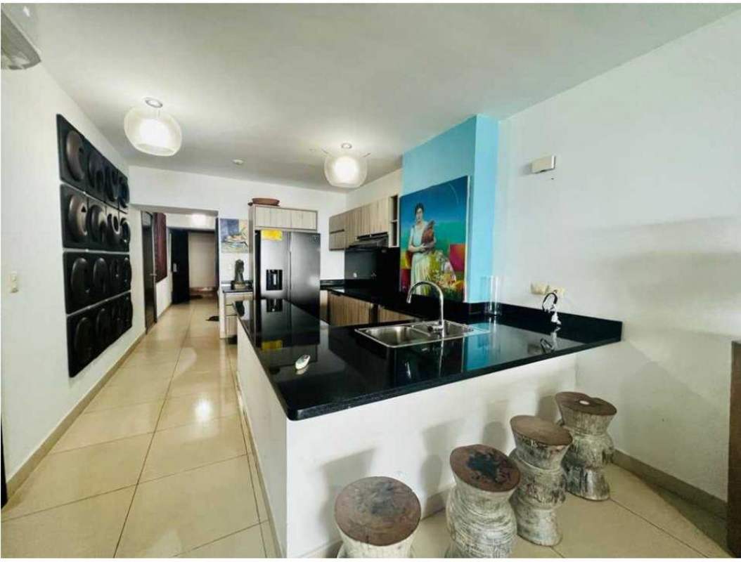 Elegant kitchen with granite countertop, island, and pendant lighting at PH Rivage Tower apartment Panama