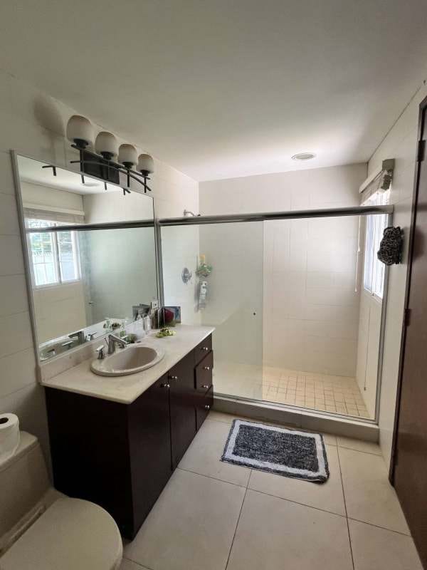 Bathroom with clear glass shower, beige tile, mirror in family house for sale Panama City