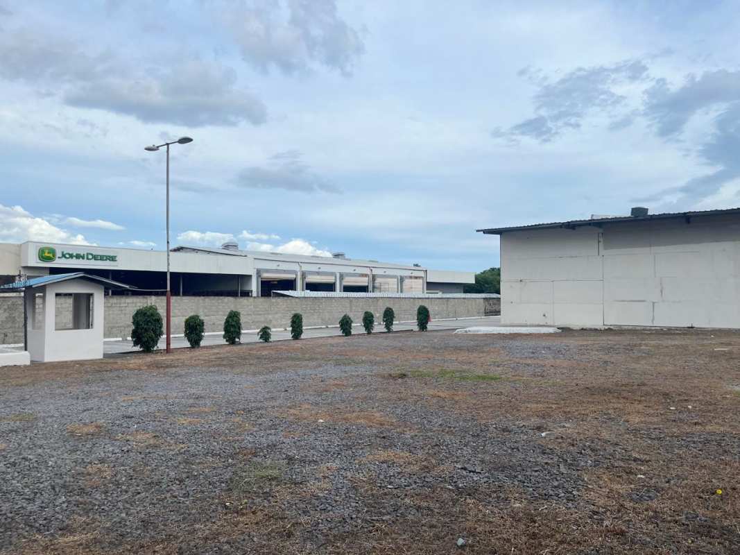 Entrance of flat commercial-industrial land with security pavement and structures visible from main road Panama
