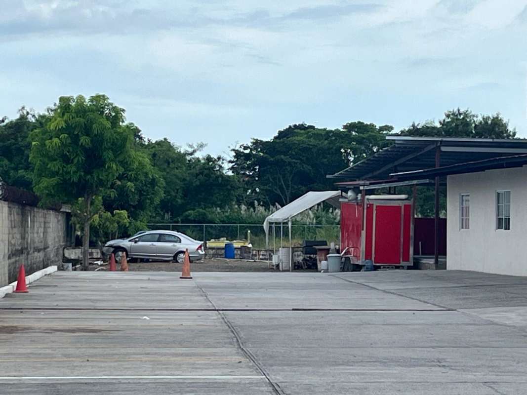 Modern commercial complex adjacent to lot with parking and signage visible Panama City