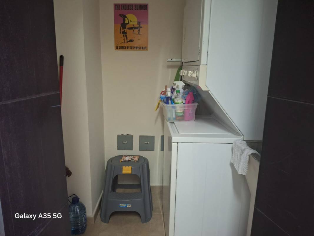 Compact laundry space with stacked washer dryer and cleaning supplies in PH Bayfront Tower Avenida Balboa Panama