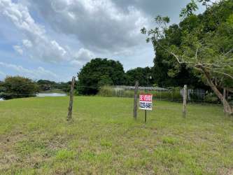 Rural paved road with grassy lot and lake nearby Lagomar San Carlos Panama land for development
