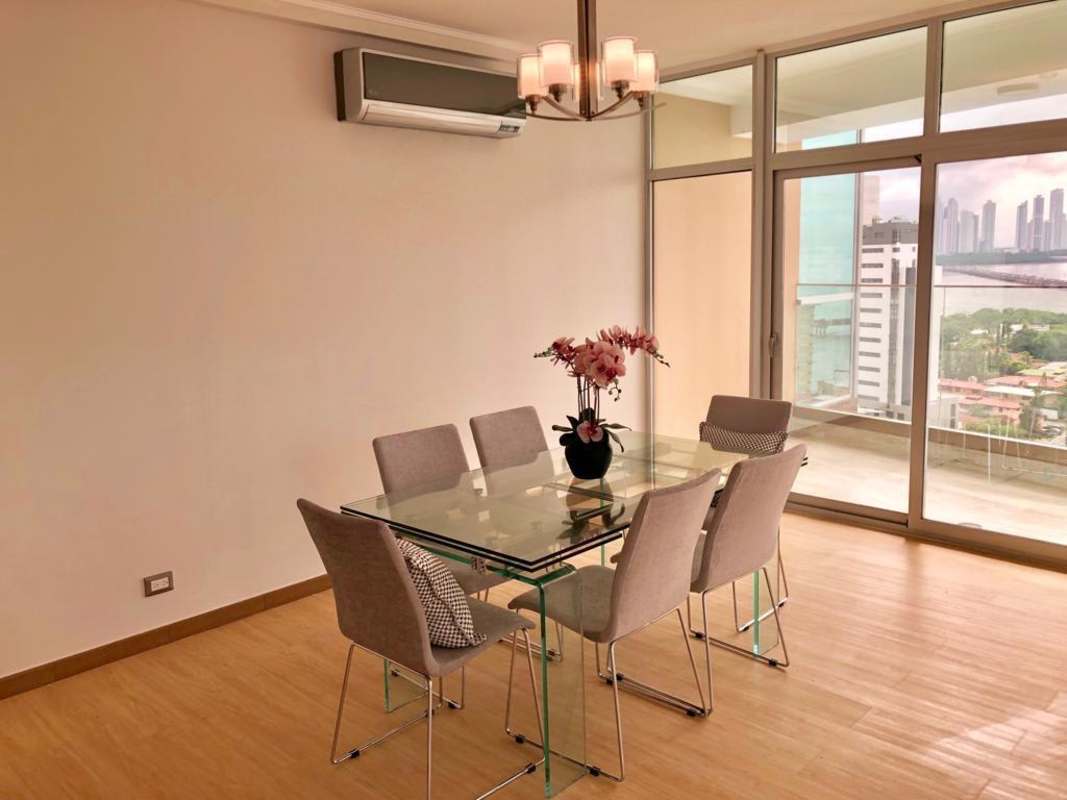 Dining room with glass table and ocean skyline view in PH Coco Place Panama City
