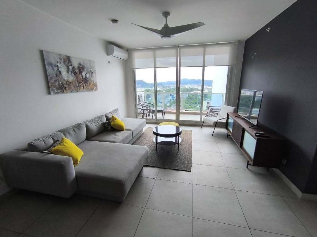 Living room with grey sectional sofa balcony city view PH Van Gogh El Cangrejo apartment rental