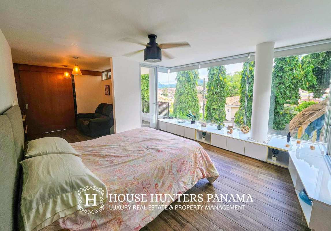 Master bedroom with floor-to-ceiling windows, wood floors and garden view in Altos de Panamá house