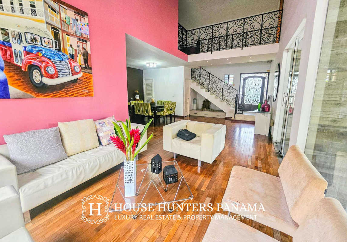 Spacious living area with vaulted ceiling, stylish staircase, wood floors in upscale home in Panama City