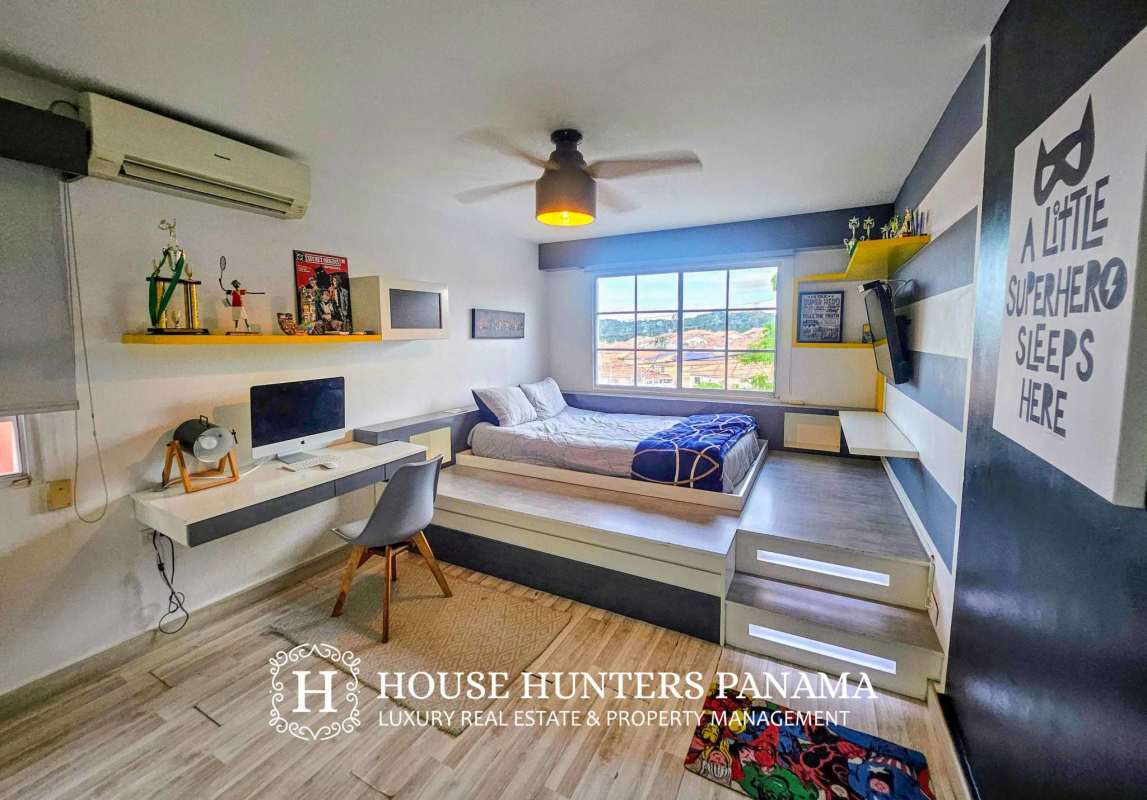 Modern bedroom with platform bed, floating desk, striped decor and large window in luxury home Panama