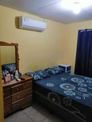 Simple bedroom with AC, blue bedding, and yellow walls in Residencial El Laurel La Chorrera