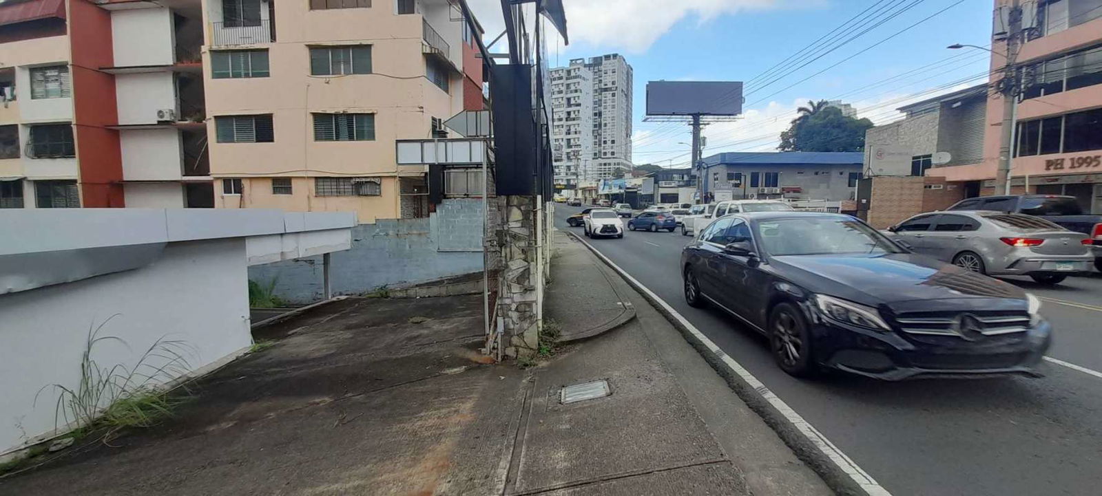 Busy Via Porras commercial street with storefront visibility and fenced lot Panama