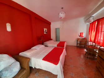 Bright twin bedroom with red accent wall, traditional furniture, tile floor in Panama beach villa vacation rental