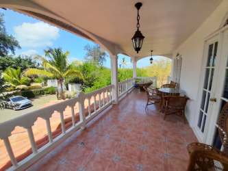 Large covered balcony with arched openings, Mediterranean decor, patio furniture and garden view in Panama beach house