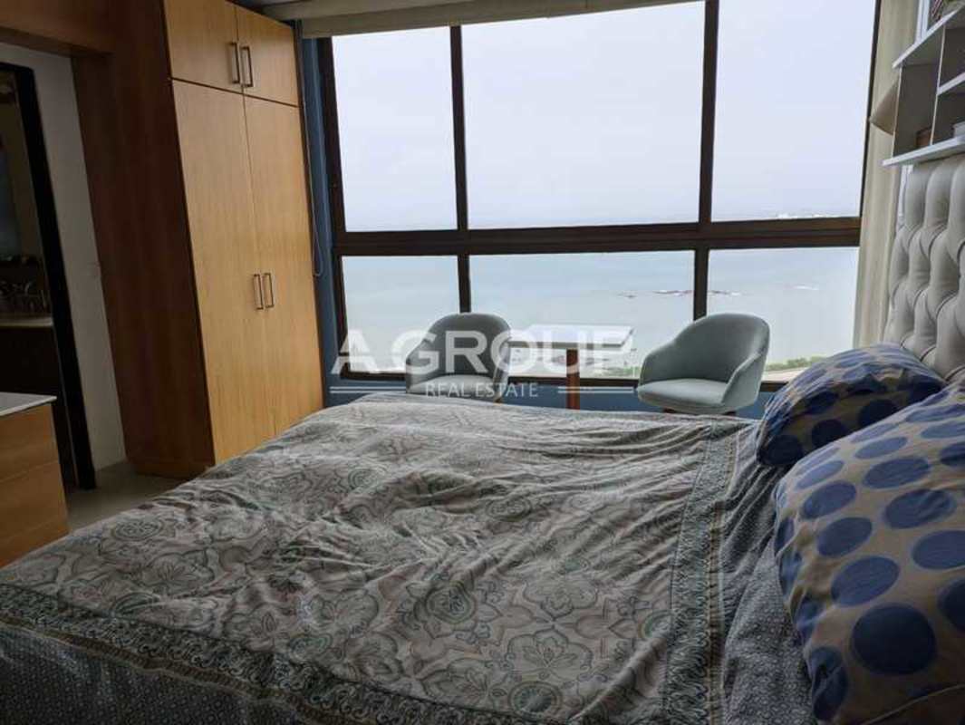 Bright kitchen with granite countertops, double sink, wood cabinets, appliances and large windows in Panama condo