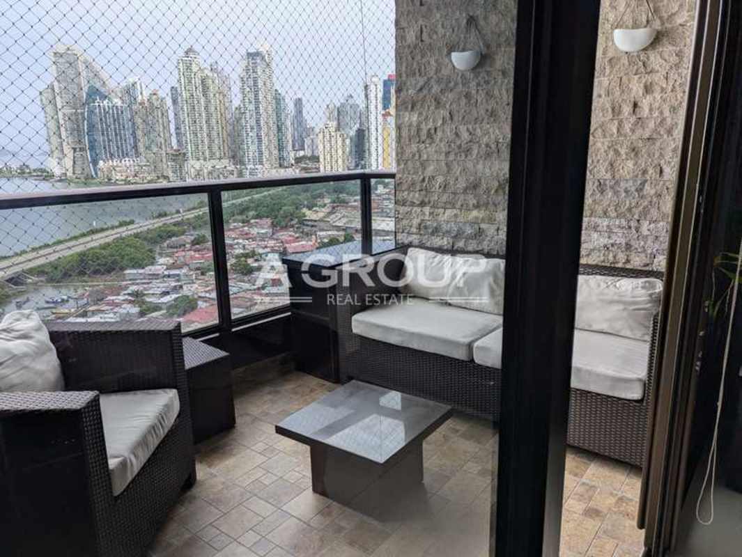 Modern living room with leather sofas, panoramic waterfront views, stone accent wall, glass coffee table in Panama luxury condo