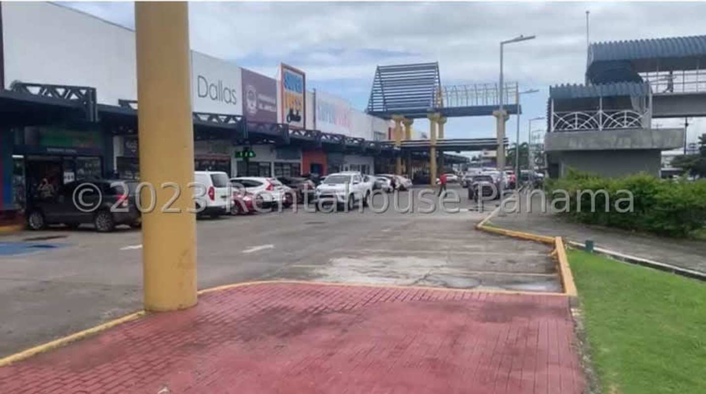 Shopping plaza exterior with parking, pedestrian bridge and storefronts in Los Pueblos Panama