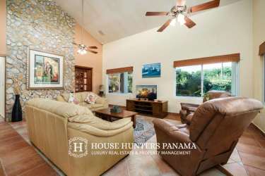 Large living space with vaulted ceiling, stone accent wall, and mountain views in Boquete home