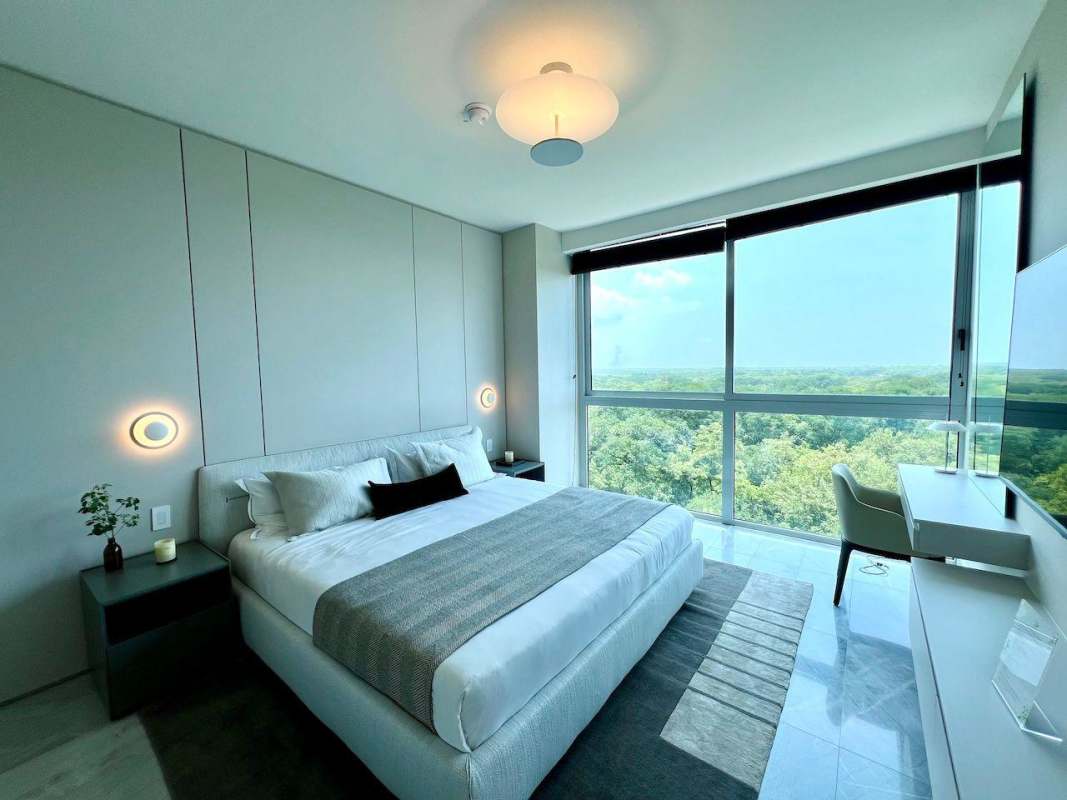 Modern bedroom with floor-to-ceiling windows overlooking golf course in The Ivy Panama