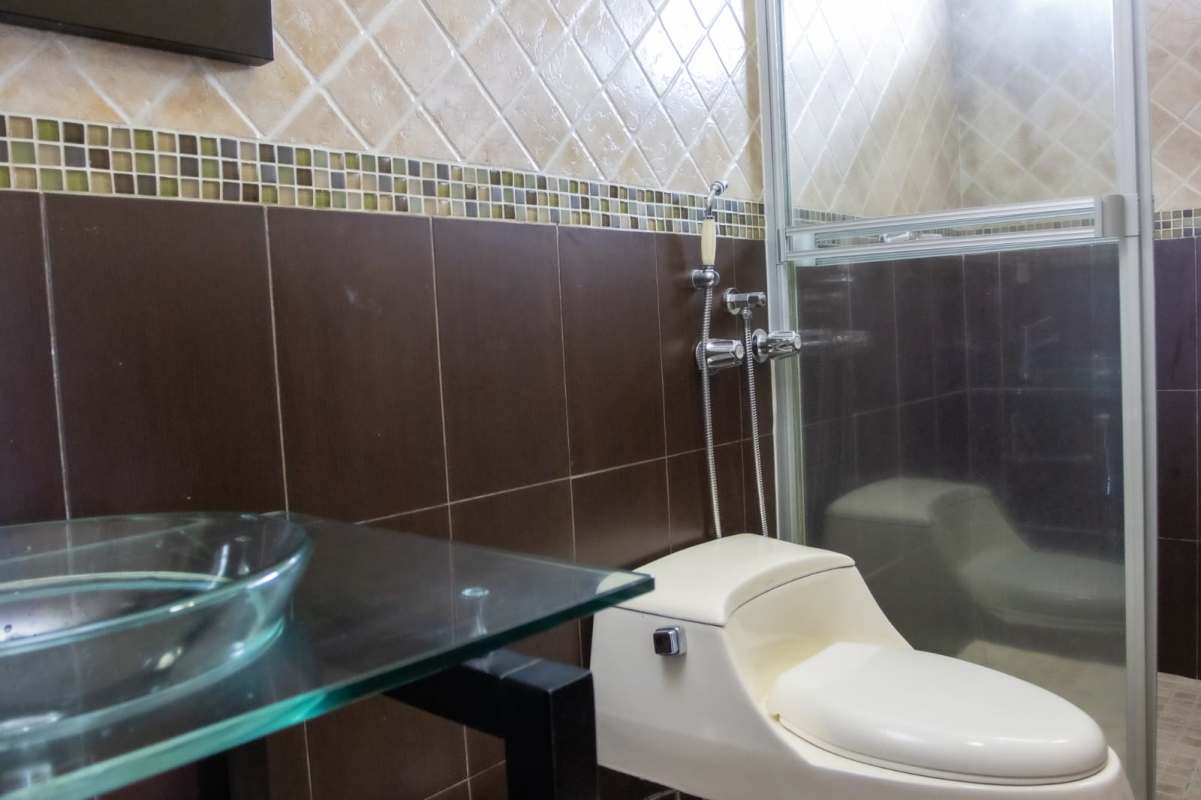 Modern bathroom with vessel sink, toilet and glass shower in Costa del Este house