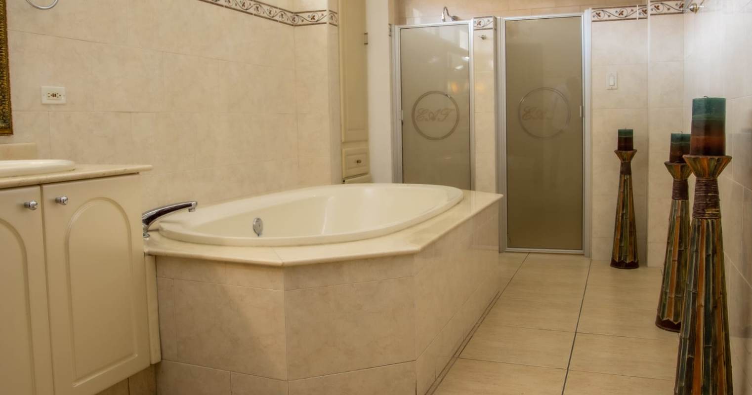 Traditional master bath with built-in tub, enclosed shower, and marble finishes Costa del Este