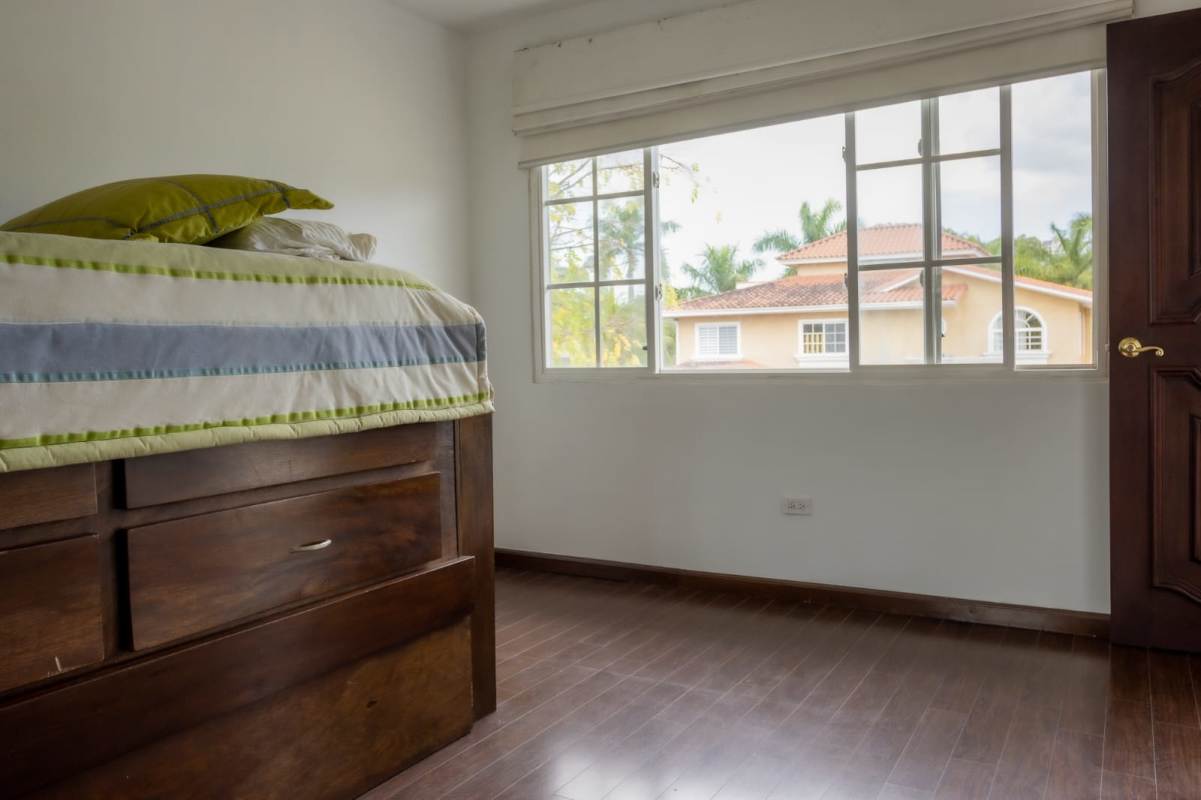 Bedroom with wooden bedframe, large window and garden views in Costa del Este home