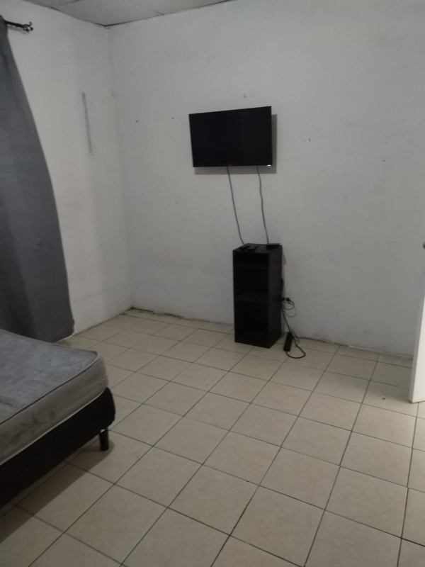 Bedroom with wall-mounted TV, small shelving, tiled floor in Panama City rental