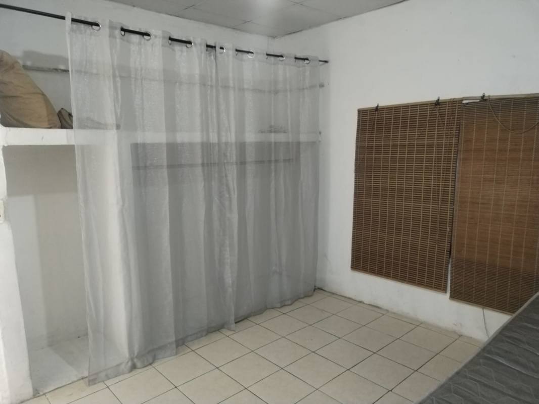 Bedroom space with curtain divider, built-in shelf, tile floor in Panama City apt