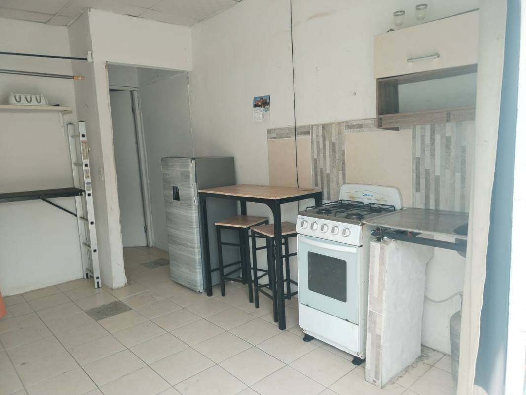 Minimalist kitchen with fridge, gas stove, countertop and open shelves in Juan Díaz apartment