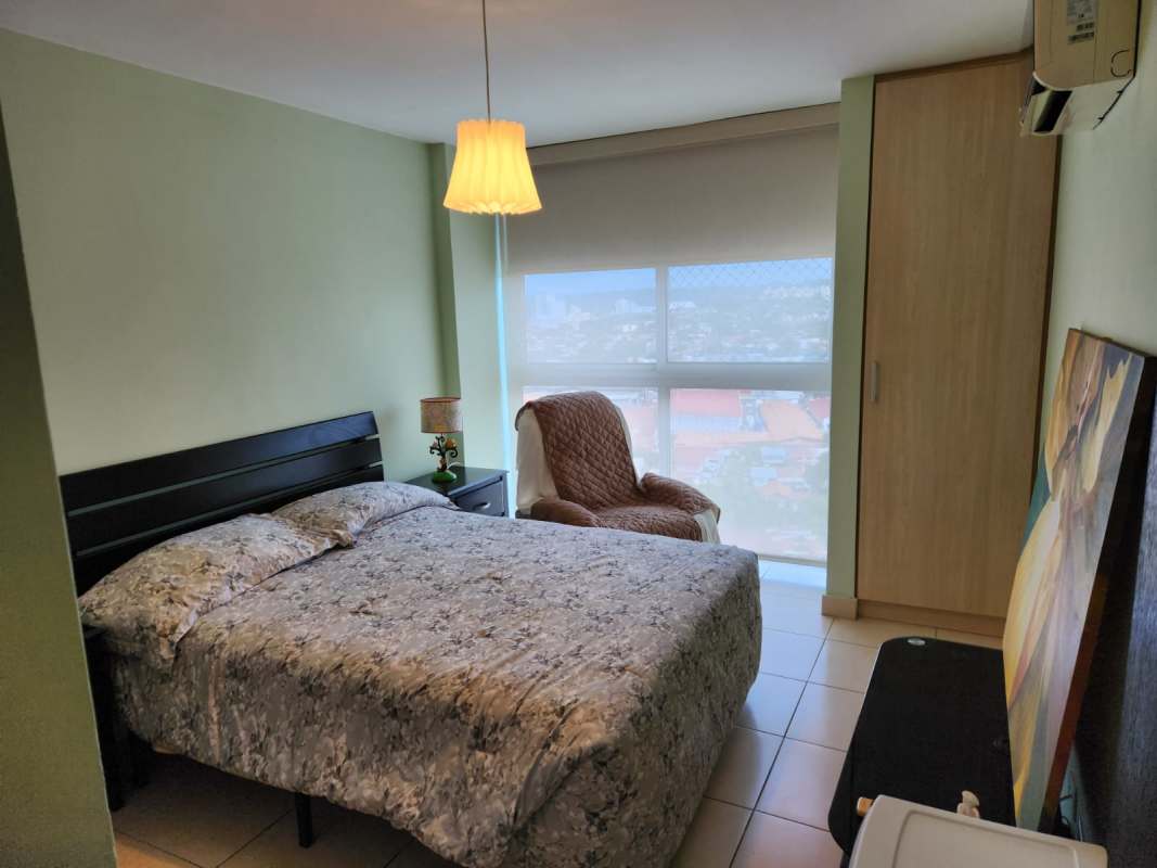Bedroom with city view window, built-in wardrobe, floral bedding at PH Ecco Tower Hato Pintado Panama