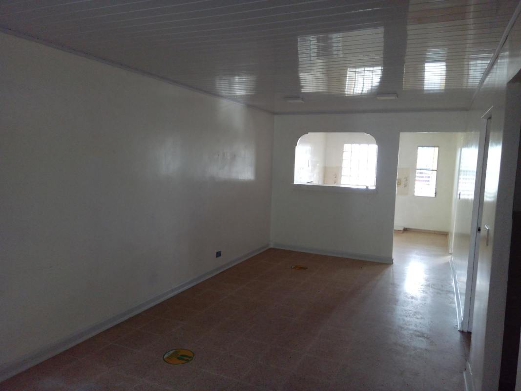 Empty tiled interior living room with white walls and arched opening to kitchen Linda Vista Panama house for sale
