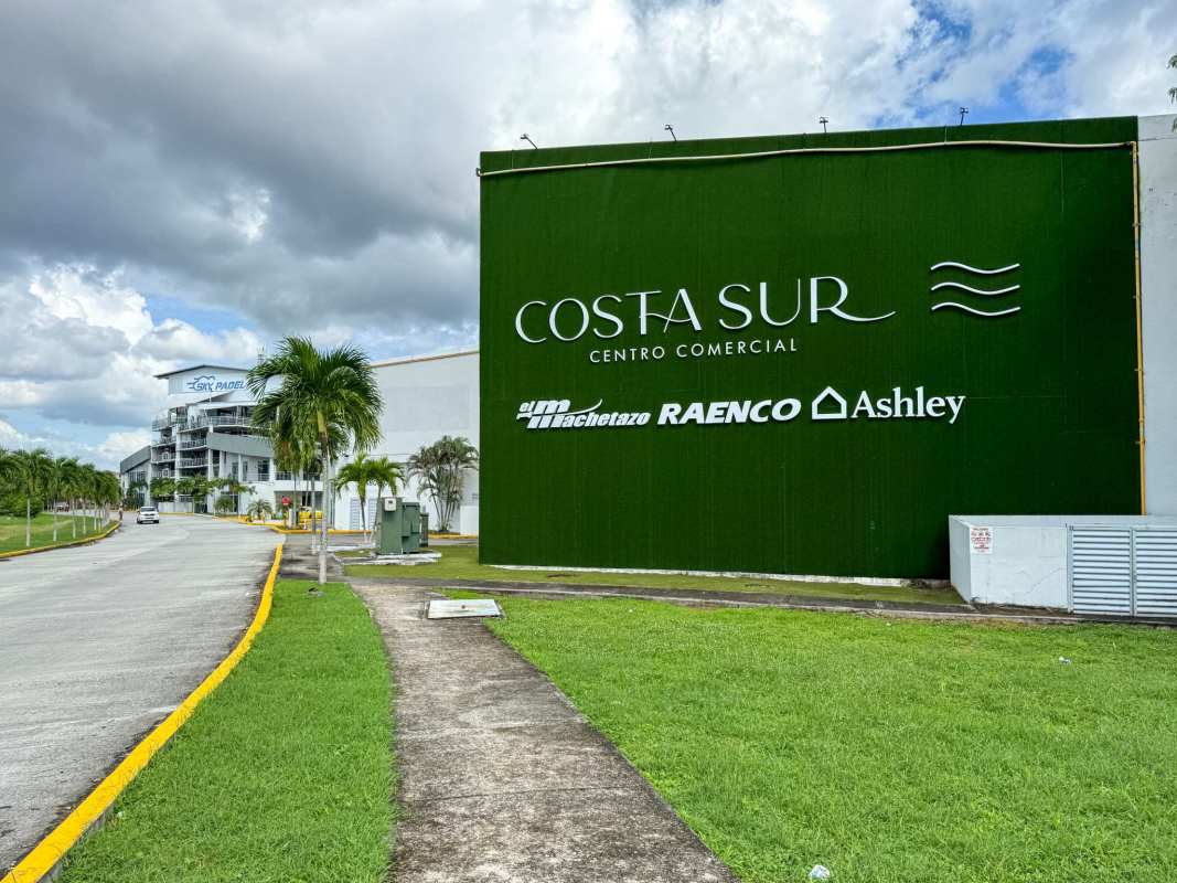 Panoramic shopping plaza exterior with glass storefronts and parking at Costa Sur Plaza Panama