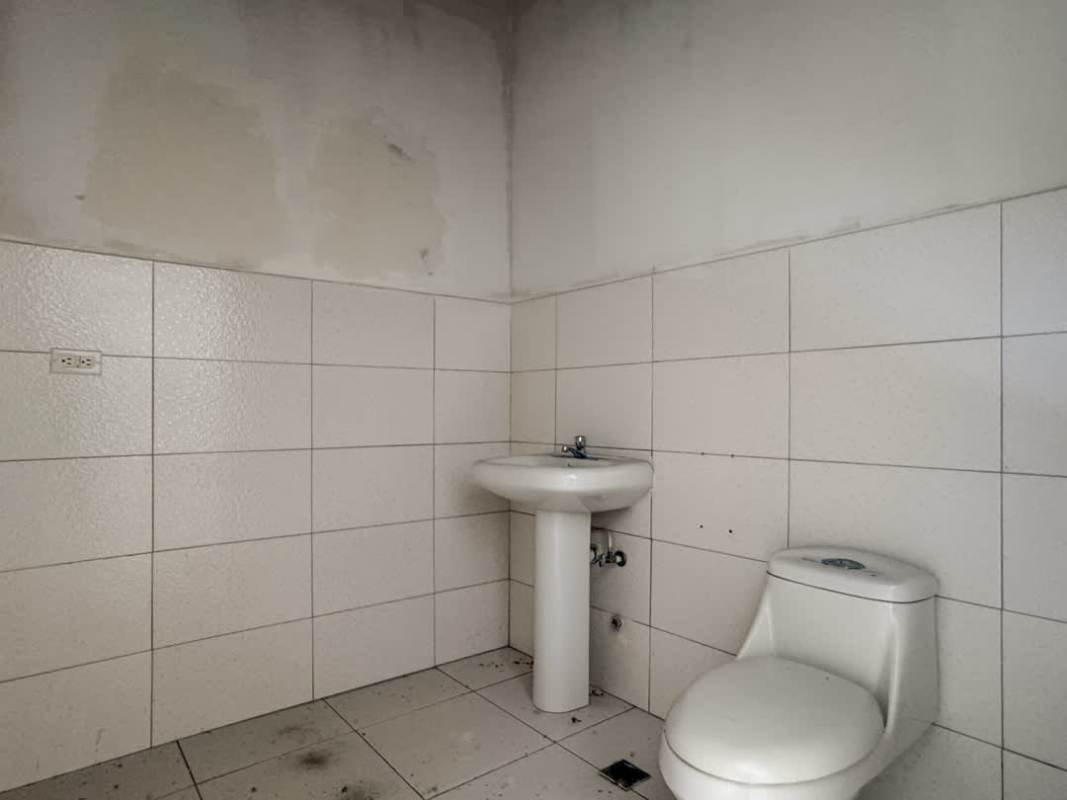 Simple private bathroom with white tiles in commercial retail unit Costa Sur Plaza Panama