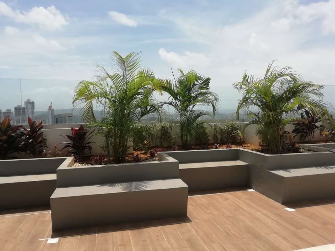 Rooftop terrace with built-in seating, tropical plants and skyline view at PH Panoramic Tower